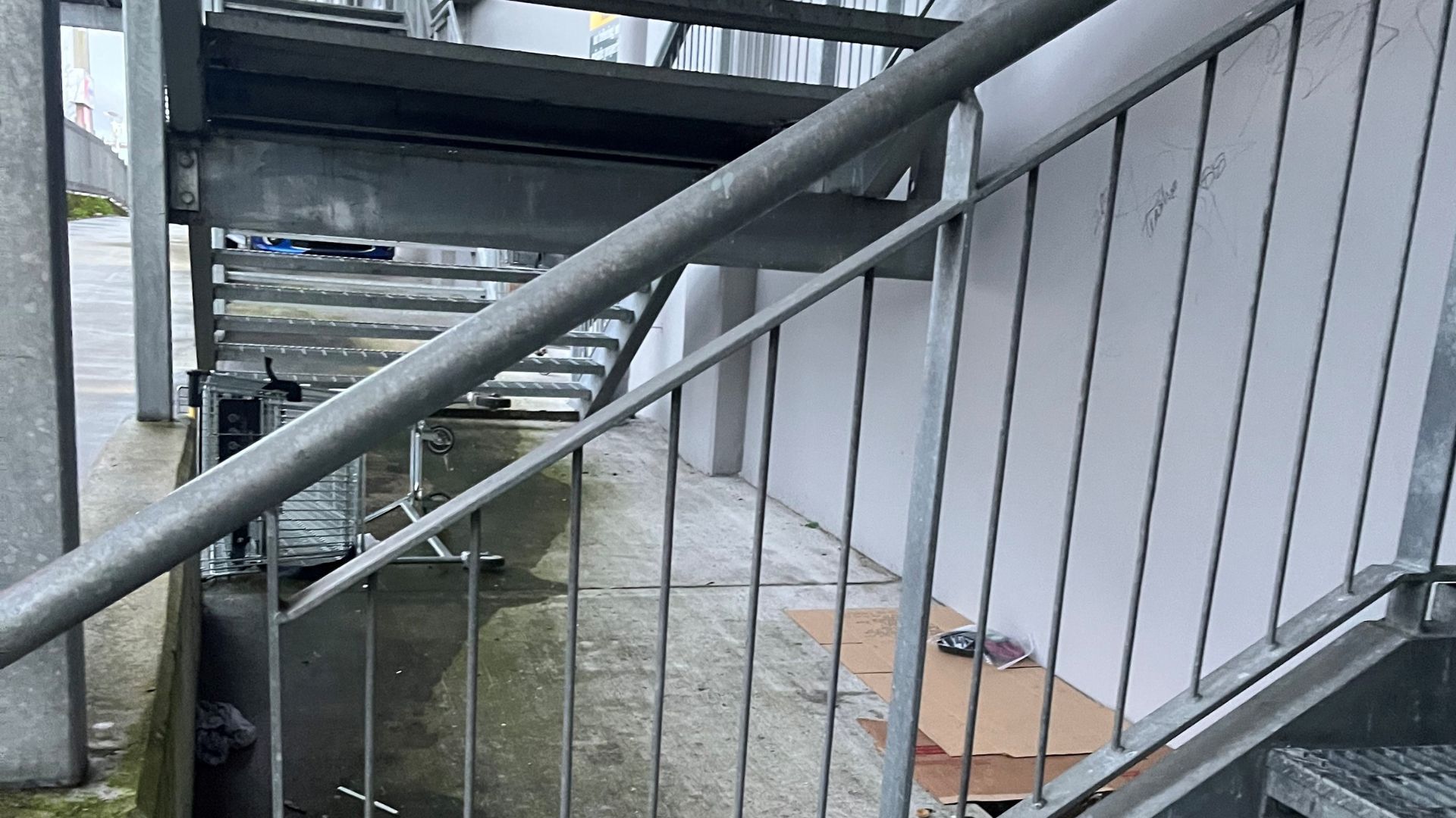 Flattened cardboard boxes under the stairs of a commercial building suggest someone has been sleeping here.